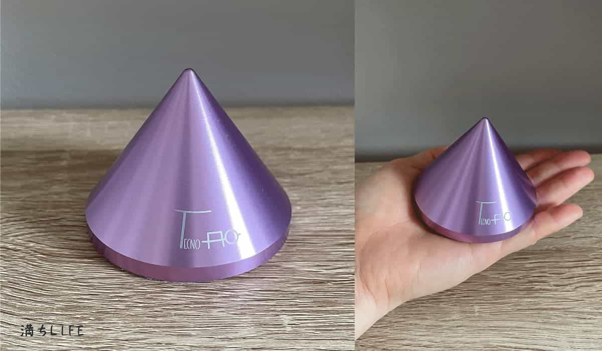 ミニエネルギーバランサー（TAMB01）の本体と、手のひらに乗せたサイズ感の比較写真。直径7cm、高さ5.5cmの円錐型の電磁波対策グッズ。パープルの金属製。
